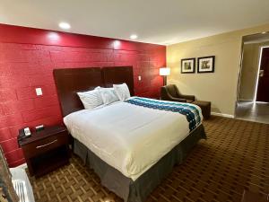 a hotel room with a bed and a red wall at Royal Inn - North Augusta - Home Of The Masters - Augusta Downtown in Beech Island