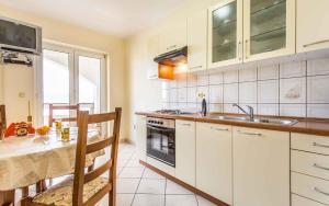 cocina con armarios blancos, mesa y fregadero en Apartment in Vrbnik - Insel Krk 13594, en Vrbnik