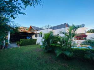 une maison blanche avec une cour plantée de palmiers dans l'établissement Joyau secret # Jardin # Piscine # Bien-être # prox centre ville, à Antananarivo