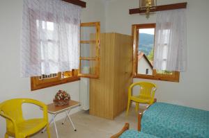 a living room with yellow chairs and a table and windows at Elati Apartments in Elati