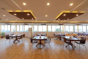 a dining room with tables and chairs and windows at VOVO HOTELS in Yelahanka