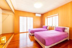Habitación con 2 camas, suelo de madera y ventanas. en えびす家, en Ishigaki Island