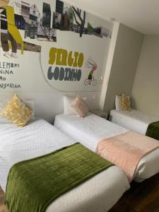 Habitación con 3 camas con sábanas verdes y blancas en Guest House Stories, en Beja