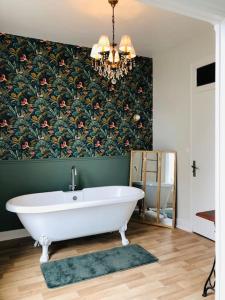 y baño con bañera y papel pintado con motivos florales. en Appartement « Le B » à Baccarat, en Baccarat