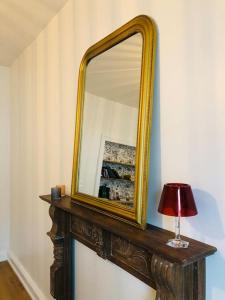 un espejo en una pared con una lámpara en una mesa en Appartement « Le B » à Baccarat, en Baccarat