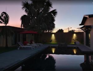 a pool with two chairs and a umbrella and a palm tree at CALME ET SERENITE A LA RIVIERE in Saint-Louis