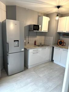 a kitchen with white cabinets and a refrigerator at Jolie appartement duplex 2 min gare-Disney et paris 15 min in Noisy-le-Grand