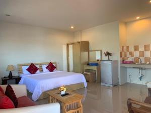 a bedroom with a large white bed and a kitchen at Da Bungalows in Kata Beach