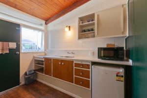 una pequeña cocina con fregadero y microondas en Aaryn Court Motel, en Rotorua