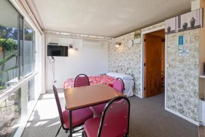 a room with a table and chairs and a bed at Aaryn Court Motel in Rotorua