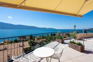 balcón con mesa, sillas y vistas al océano en Hotel Villa Europa, en Gargnano