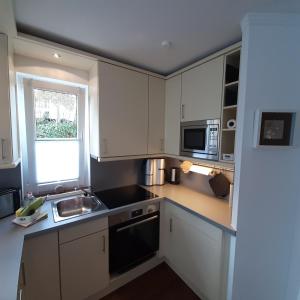 uma cozinha com armários brancos, um lavatório e uma janela em Seestern em Grömitz