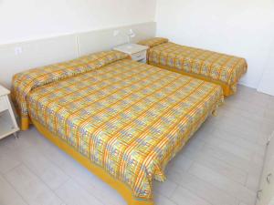 2 Betten in einem Zimmer mit einer karierten Bettdecke in der Unterkunft Holiday Homes in Bibione 36266 in Bibione