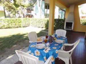 einen Tisch mit einem blauen Tischtuch und weißen Stühlen in der Unterkunft Holiday Homes in Bibione 36266 in Bibione