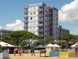 a tall apartment building with people walking on the beach at Apartments in Bibione 36469 in Bibione