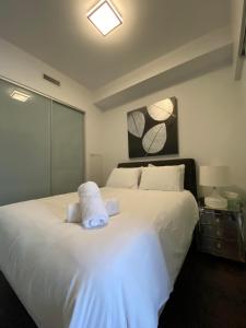 een slaapkamer met een groot bed met witte lakens en kussens bij RivetStays - Quaint 1-Bedroom Steps from CN Tower, MTCC, Union Station in Toronto