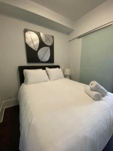 ein weißes Bett mit zwei Handtüchern darüber in der Unterkunft RivetStays - Quaint 1-Bedroom Steps from CN Tower, MTCC, Union Station in Toronto