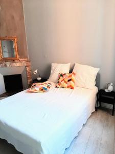 a bed with white sheets and colorful pillows on it at Appartement Pont des Catalans in Toulouse