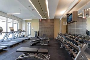 een fitnessruimte met rijen loopbanden en een flatscreen-tv bij RivetStays - Quaint 1-Bedroom Steps from CN Tower, MTCC, Union Station in Toronto