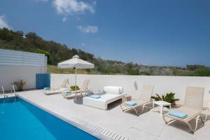 a pool with lounge chairs and an umbrella next to a swimming pool at Casa de Nicole in Protaras