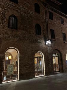 un bâtiment en briques avec des fenêtres cintrées et un panneau sur celui-ci dans l'établissement Hotel Bel Soggiorno, à San Gimignano