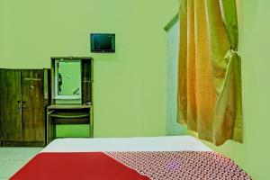 een slaapkamer met een bed en een tv aan de muur bij OYO 92467 Cahyo Kost 1 in Semarang