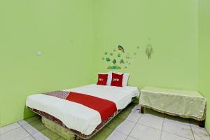 um quarto com uma cama com almofadas vermelhas em OYO 92467 Cahyo Kost 1 em Semarang