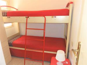 a bedroom with two bunk beds with red sheets at Holiday home in Bibione 41086 in Bibione