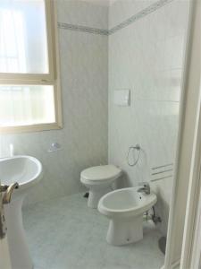 ein weißes Bad mit einem WC und einem Waschbecken in der Unterkunft Holiday home in Bibione 41086 in Bibione