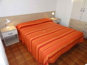 - une chambre avec un lit et une couverture rayée orange dans l'établissement Apartments in Bibione 24607, à Bibione
