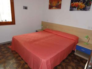 1 dormitorio con 1 cama con colcha roja en Apartment in Bibione 38360, en Bibione