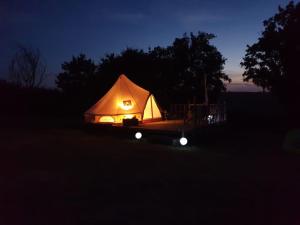 oświetlony namiot na polu w nocy w obiekcie Camping La Petite Houmée w mieście Curzay-sur-Vonne