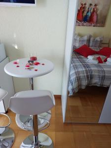 uma pequena mesa branca e banco num quarto com uma cama em Joli studio avec terrasse et vue EXCLUSIVEMENT POUR NON FUMEURS em Belmont-sur-Lausanne