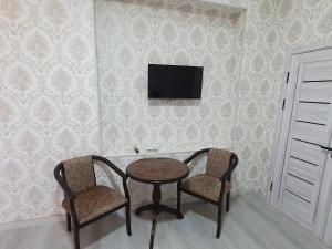 a table and two chairs and a tv on a wall at Comfort Tashkent in Tashkent