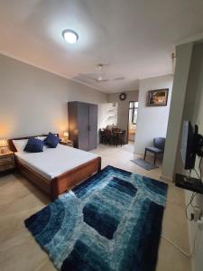 a bedroom with a bed and a blue rug at Spacious Holiday Let Wi-Fi & Private Amenities Oyibi in Oyibi
