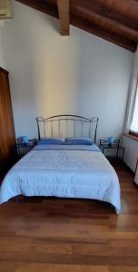 a bedroom with a bed with blue sheets and two windows at Casa Adige in Verona
