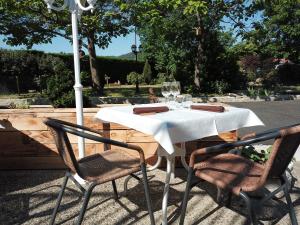 Biały stół z dwoma krzesłami i parasolem w obiekcie Hotel Les Glycines w mieście Vieille-Brioude
