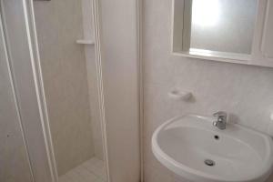 a white bathroom with a sink and a shower at Apartment in Rosolina Mare 43995 in Rosolina Mare