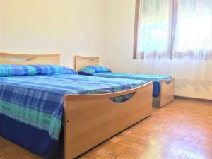 a bedroom with two beds with blue sheets and a window at Holiday home in Bibione 36470 in Bibione