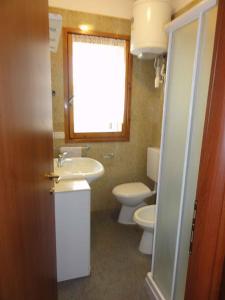 ein Bad mit einem Waschbecken, einem WC und einem Fenster in der Unterkunft Holiday home in Bibione 38311 in Bibione