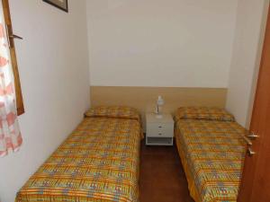 2 Betten in einem kleinen Zimmer mit einem Nachttisch in der Unterkunft Holiday home in Bibione 38311 in Bibione