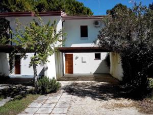 ein weißes Haus mit einer Holztür im Hof in der Unterkunft Holiday home in Bibione 38311 in Bibione