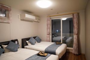 函館市にあるHakodate MOTOMACHI guesthouseのベッド2台と窓が備わるホテルルームです。