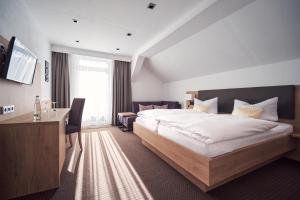 コッヘル・アム・ゼーにあるゼーホテル グラウアー ベアの大きなベッドとデスクが備わるホテルルームです。