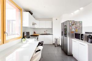 een keuken met witte kasten en een roestvrijstalen koelkast bij Magnifique appartement 160m2 à 15mn de Paris in Vitry-sur-Seine