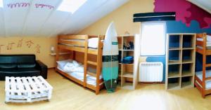 a room with bunk beds with a surfboard in it at Surfhousegerra in San Vicente de la Barquera