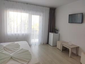 a white bedroom with a bed and a television at Vila Marius 2 Mai in 2 Mai