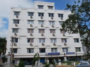 un edificio blanco con ventanas y un coche delante de él en Bhanu Residency en Tirupati