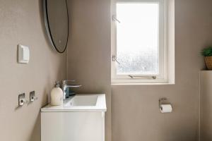 a bathroom with a sink and a window at Strandhuis de Zeeparel met hottub in Petten +24 photos