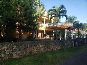 una casa grande con una pared de piedra y palmeras en 4 bedroom villa, security, private pool, ocean view, en Sosúa